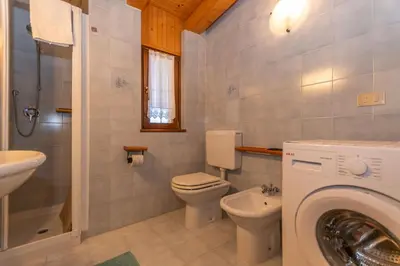 a bathroom with a toilet sink and a washing machine at Casa Paola in Rocca Pietore