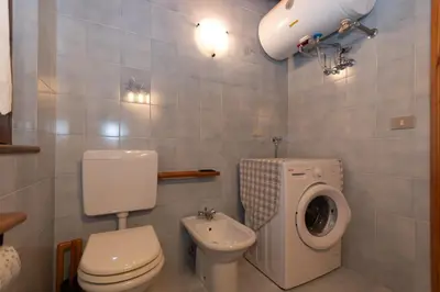 a bathroom with a toilet and a washing machine at Casa Paola in Rocca Pietore
