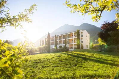 a building on a field with a mountain in the background at Haselgrund in Tirolo
