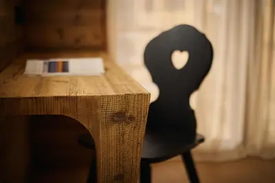 a black chair sitting next to a wooden desk at Les Pares in Corvara in Badia