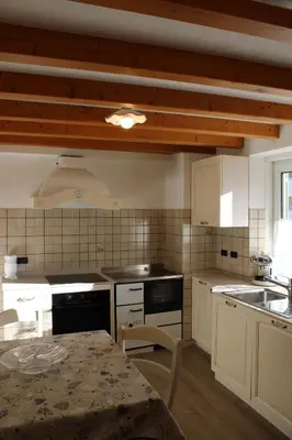 a kitchen with white cabinets and a table in it at Appartamento Ika in Canazei