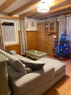 a living room with a couch and a christmas tree at Appartamento Ika in Canazei
