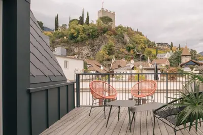 a balcony with two chairs and a view of a city at Steinach10 in Merano