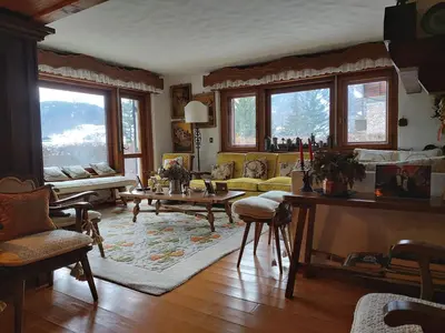 a living room with a couch and a large window at Appartamento La Montanella in Cortina dʼAmpezzo