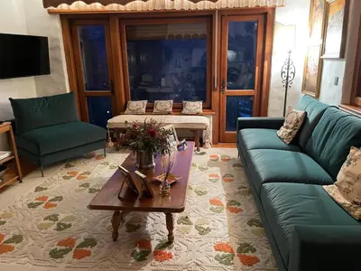 a patio with chairs and a house with mountains in the background at Appartamento La Montanella in Cortina dʼAmpezzo