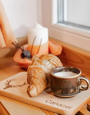 a cup of coffee and a croissant on a table at Garni Eden in Canazei