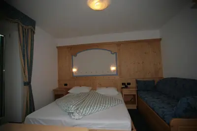 a small room with a bed and a couch at Garni Eden in Canazei