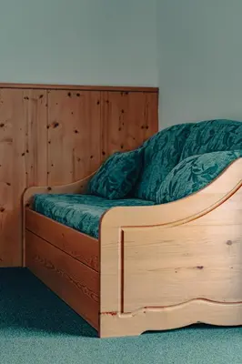 a wooden bed with a green comforter on it at Garni Eden in Canazei