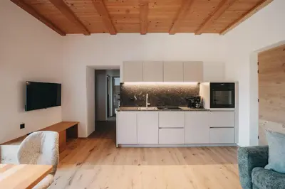 a kitchen with white cabinets and a wooden floor at Stein unter Lebenberg NEW 2026 in Cermes