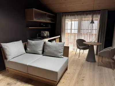 a room with a bed and a table and a kitchen at La Maison 35 - Zentrales Wohnhaus in Bruneck in Brunico