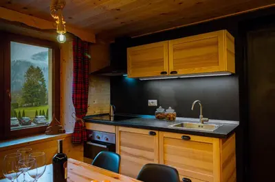 a kitchen with wooden cabinets and a sink and a table at Dolomiti Urban Lodge - casa Marmolada in Cencenighe