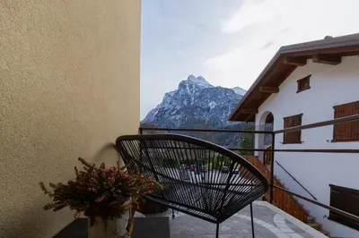 a chair on a balcony with a view of a mountain at Dolomiti Urban Lodge - casa Marmolada in Cencenighe