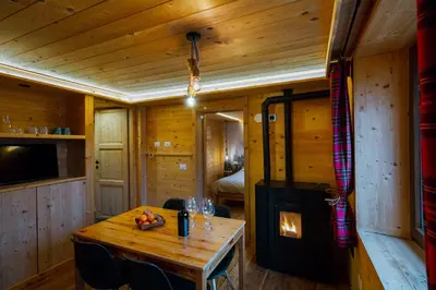a wooden dining room with a table and a fireplace at Dolomiti Urban Lodge - casa Marmolada in Cencenighe