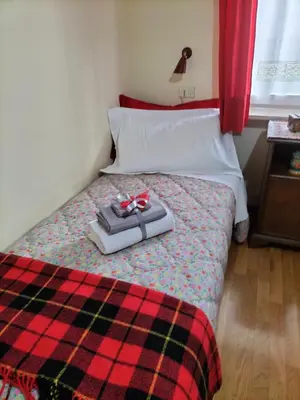 a bed with a plaid blanket and two presents on it at Appartamento l'angelo in Predazzo