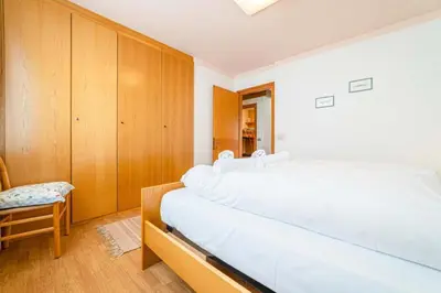 a bedroom with two beds and a chair at Appartamento Bernardi in Caprile