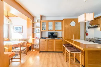 a kitchen with wooden cabinets and a dining room at Appartamento Bernardi in Caprile