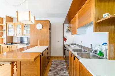 a kitchen with wooden cabinets and white counter tops at Appartamento Bernardi in Caprile