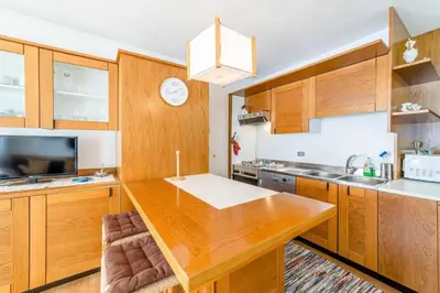 a kitchen with wooden cabinets and a large wooden table at Appartamento Bernardi in Caprile