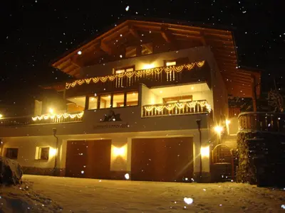 a building with a deck in the snow at night at Unterthurnerhof in Rifiano
