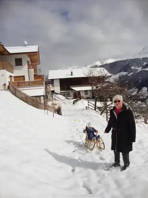 a woman pulling a child in a sled in the snow at Unterthurnerhof in Rifiano