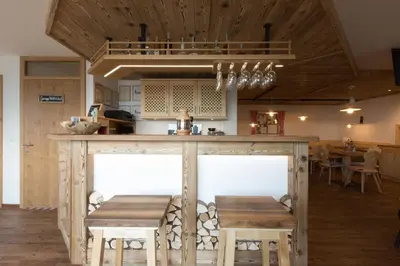 a kitchen with a wooden island with a table and stools at Unterthurnerhof in Rifiano