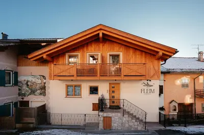 a wooden house with a balcony on top of it at Guest House Fleim in Panchia