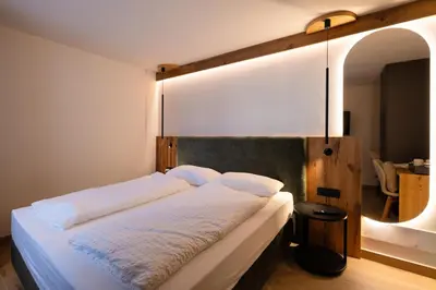 a bedroom with a large bed with white sheets at Guest House Fleim in Panchia