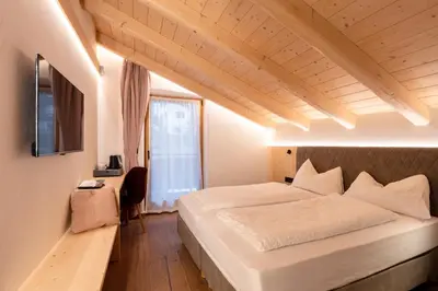 a bedroom with a large white bed and a window at Guest House Fleim in Panchia
