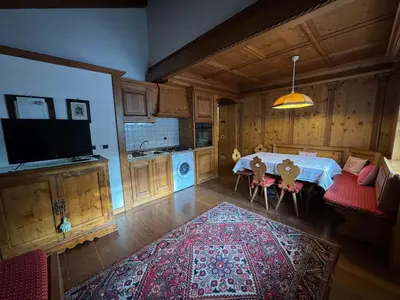 a living room with a table and a kitchen at Mansarda Ca Geranei in San Vito di Cadore