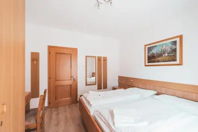 a bedroom with red curtains and a bed and a chair at Casa Pettena in Pozza di Fassa