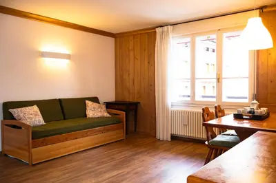 a living room with a green couch and a table at Comodo appartamento a San Vito di Cadore in San Vito di Cadore