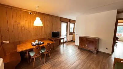 a living room with a wooden table and a television at Comodo appartamento a San Vito di Cadore in San Vito di Cadore