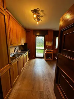 a kitchen with wooden cabinets and a wooden floor at Chalet Sofia in San Vito di Cadore