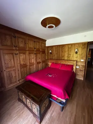a bedroom with a large pink bed with wooden cabinets at Chalet Sofia in San Vito di Cadore