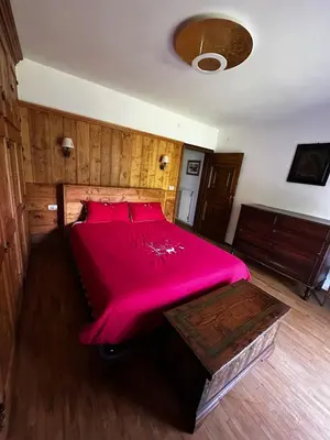 a bedroom with a large bed with a red bedspread at Chalet Sofia in San Vito di Cadore