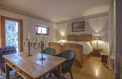 a bedroom with a bed and a table and chairs at Monolocale romantico tra le vette di Cortina in Cortina dʼAmpezzo