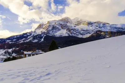 a snow covered mountain with a house on a snow covered slope at Monolocale romantico tra le vette di Cortina in Cortina dʼAmpezzo