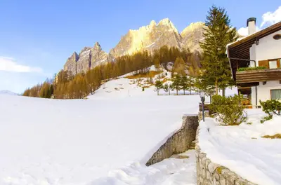 a snow covered field in front of a mountain at Monolocale romantico tra le vette di Cortina in Cortina dʼAmpezzo