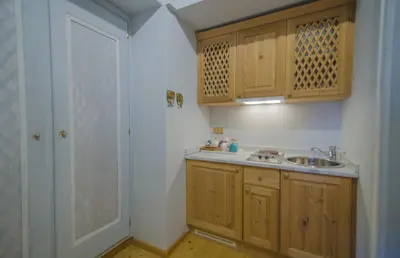 a small kitchen with a sink and wooden cabinets at Monolocale romantico tra le vette di Cortina in Cortina dʼAmpezzo