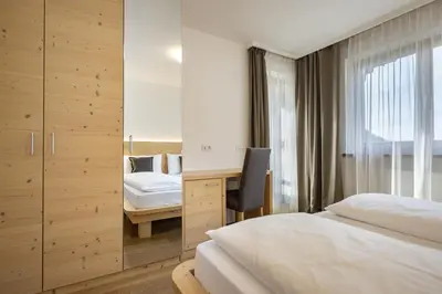 a hotel room with two beds and a desk at Apartments Monica in Santa Cristina in Val Gardena