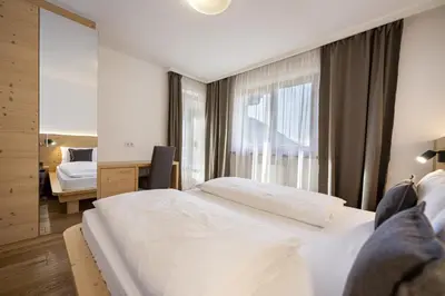a hotel room with two beds and a mirror at Apartments Monica in Santa Cristina in Val Gardena