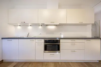 a kitchen with white cabinets and a sink at Apartments Monica in Santa Cristina in Val Gardena