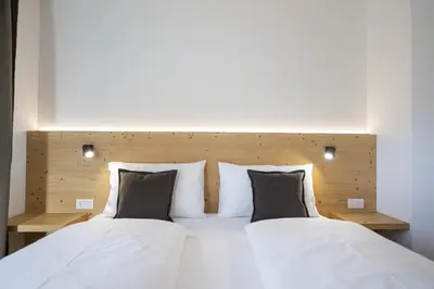 a bedroom with two beds with white sheets and pillows at Apartments Monica in Santa Cristina in Val Gardena