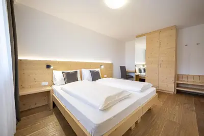a bedroom with a large bed with a wooden headboard at Apartments Monica in Santa Cristina in Val Gardena