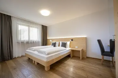 a bedroom with a bed and a desk and a chair at Apartments Monica in Santa Cristina in Val Gardena