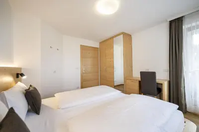 a hotel room with two beds and a desk at Apartments Monica in Santa Cristina in Val Gardena