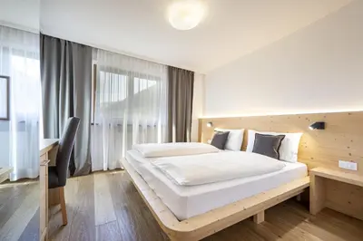 a bedroom with a large bed and a desk at Apartments Monica in Santa Cristina in Val Gardena