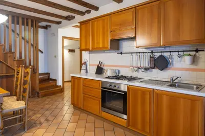 a kitchen with wooden cabinets and a stove top oven at Appartamento Al Cirmolo - 4 Camere in Pieno Centro di Fiera di Primiero in Fiera di Primiero