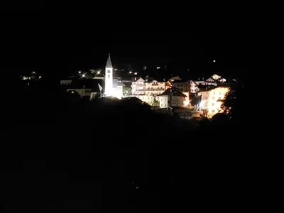 a city lit up at night with a church at Sole & Luna Dolomiti House in Voltago