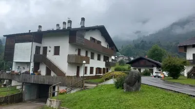 a white building with a balcony on a street at Sole & Luna Dolomiti House in Voltago